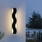 Luminaire mural LED aluminium noir au design ondulé diffusant une lumière chaleureuse.