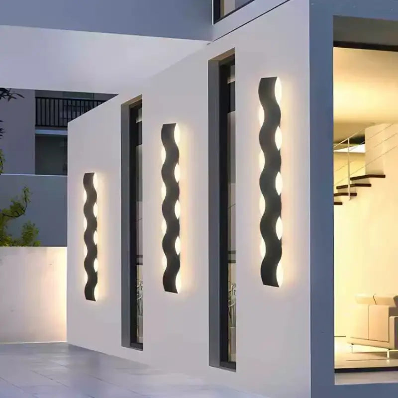 Lampe murale extérieure LED noire au motif ondulé diffusant une lumière chaude.
