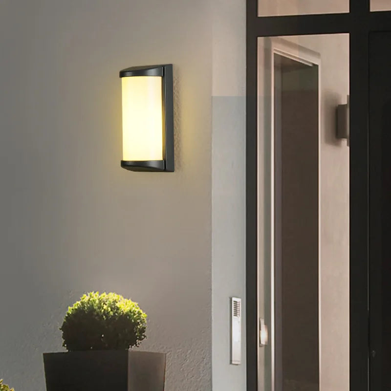Luminaire mural extérieur LED étanche en aluminium, brillant intensément près d'une porte vitrée la nuit.