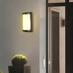 Luminaire mural extérieur LED étanche en aluminium, brillant intensément près d'une porte vitrée la nuit.