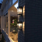 Deux appliques LED solaires Maison diffusent une élégante lumière extérieure sur un mur de briques sombre.
