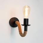 This wall lamp casts a warm industrial glow with its exposed Edison bulb and rope arm.