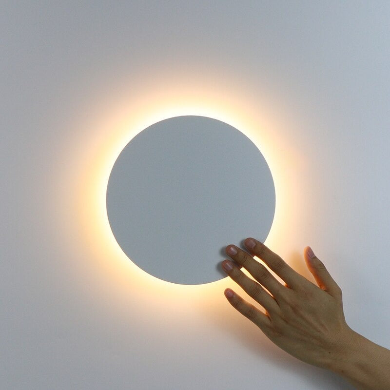 Soft, warm LED halo light radiates from a sleek circular wall fixture, creating ambiance.