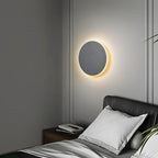 A circular LED wall light casts a cozy, warm glow for modern ambiance.