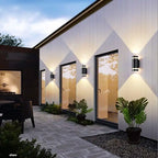 Trois appliques cylindriques noires projettent des éclats lumineux chauds en losange sur un mur blanc.