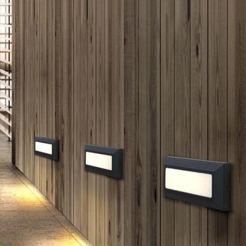 Trois appliques murales LED aluminium noir diffusent une lumière chaude, design moderne et résistant.