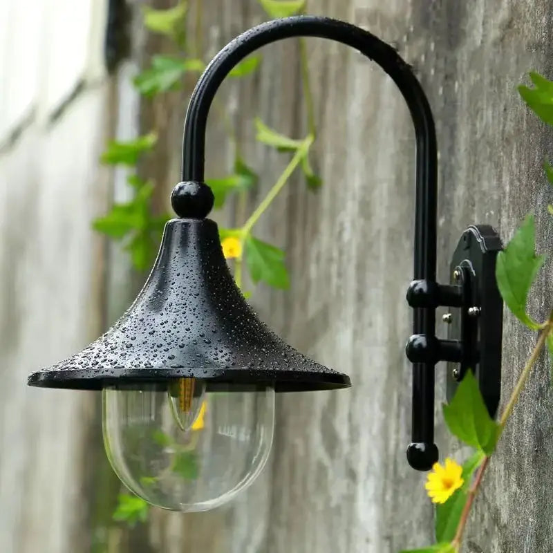 La LUMINAIRE MAISON Applique murale extérieur rétro en métal noir avec gouttelettes sur l'abat-jour.