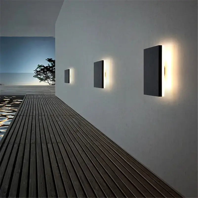 Three ORLUNE HOME Square Aluminum Wall Lights emit a soft, welcoming glow at dusk.