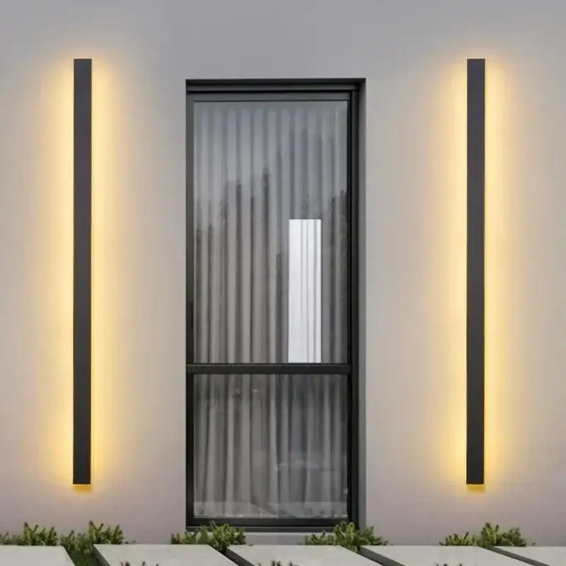 Deux appliques murales élégantes diffusent une lumière chaude sur un mur gris.
