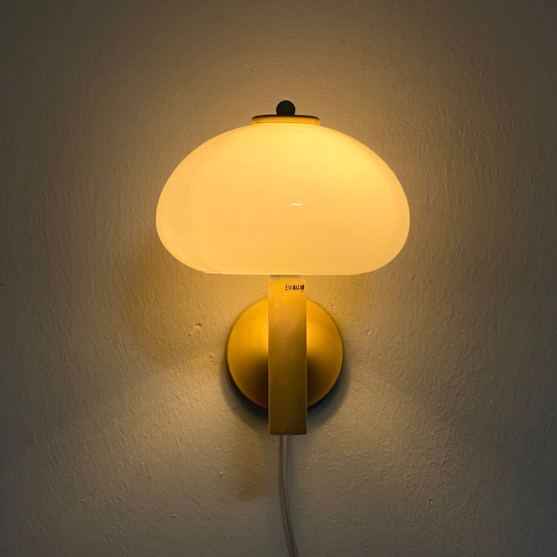 This glass wall light casts a cozy, warm glow with its frosted shade and gold accents.