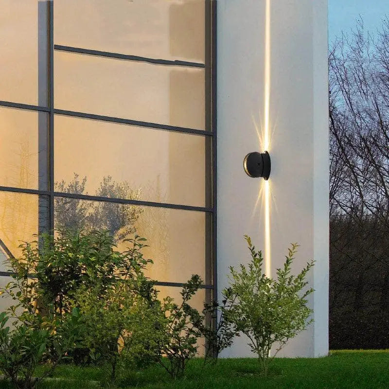 Applique murale LED aluminium moderne, lumière verticale chaude éclaire une façade blanche.