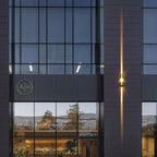 Applique murale LED moderne en aluminium installée entre de grandes fenêtres vitrées.