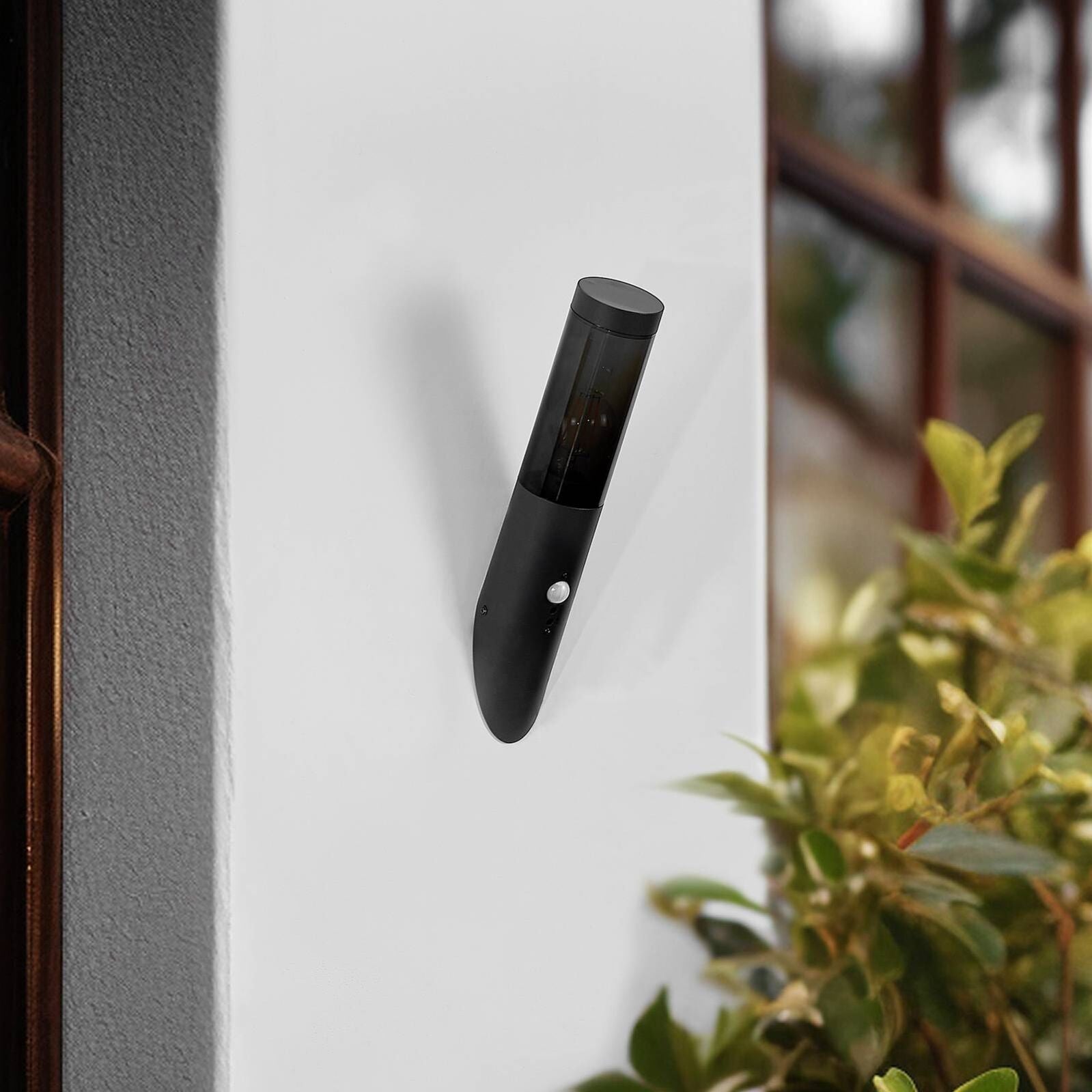 Modern black cylindrical outdoor wall light with motion sensor, showcasing sleek, minimalist design.